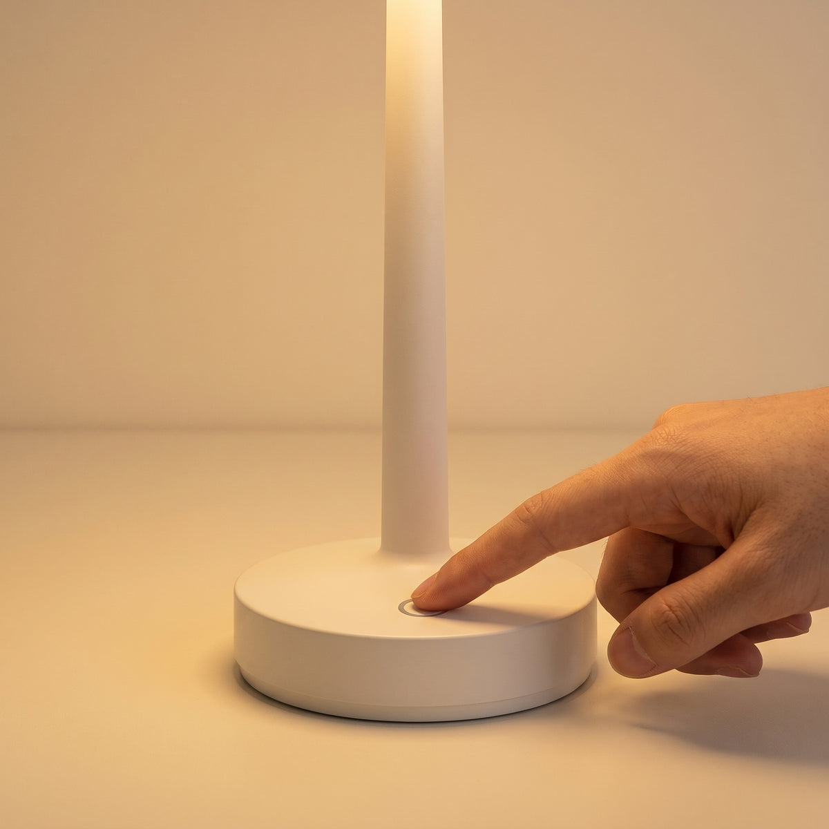 A finger tapping the touch control on the lamp's base